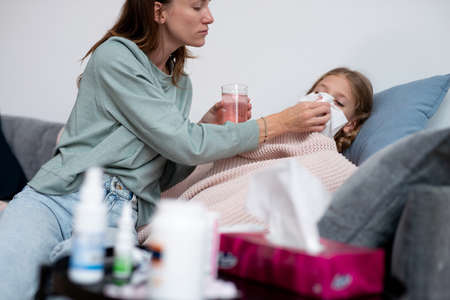 Mother wipes the nose of her sick daughterの写真素材
