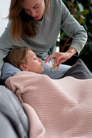 Mother uses a nasal spray to treat her daughters stuffy noseの写真素材