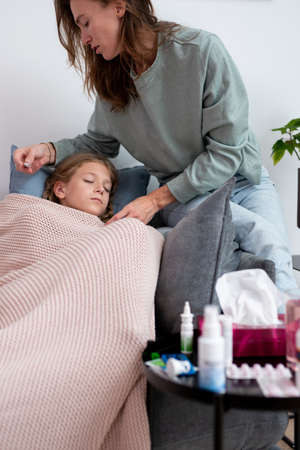 Mom takes her daughters temperature and looks at the thermometerの写真素材