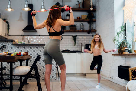 Young mother working out at home with her daughter.の写真素材