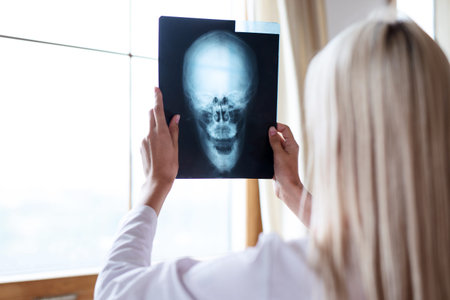 Woman doctor examines x-ray of human skull