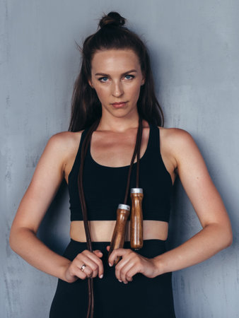 Fit young woman with a jump rope. Portrait of female athlete.