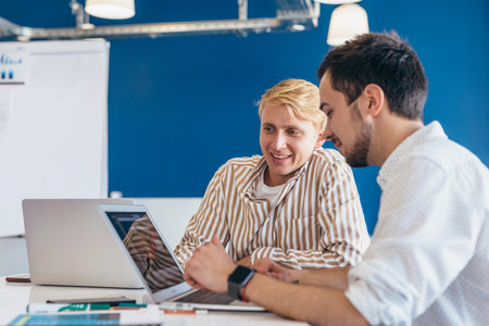 Two men working in office looking at laptop screen