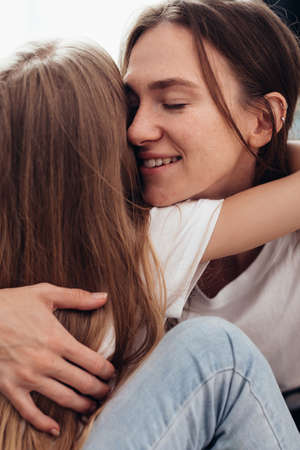 Happy mother and daughter hugging with eyes closedの写真素材