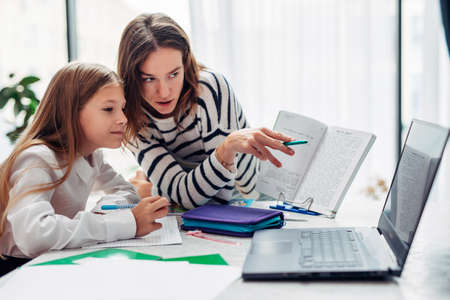 Mother and daughter watching a textbook together.の写真素材
