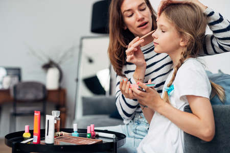 Mother applies eye shadow to her daughters eyelidsの写真素材