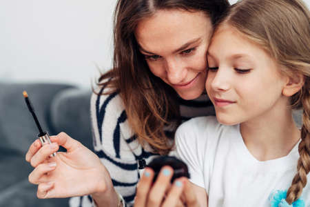 Mother and daughter doing makeup and admiring in a small mirrorの写真素材