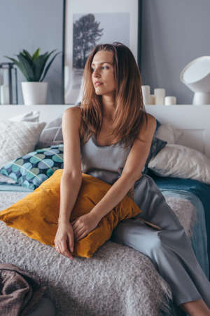 Portrait of young woman at home in bedroomの写真素材