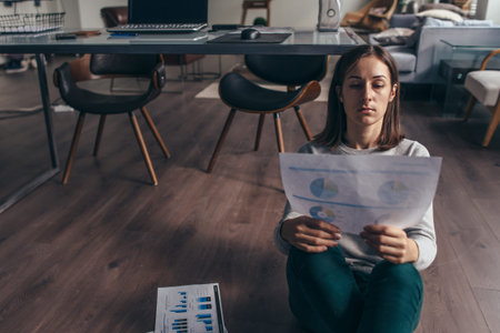 Woman sitting on the floor with official papers works with data.