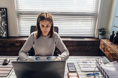 Woman works in office with laptop at worktable.