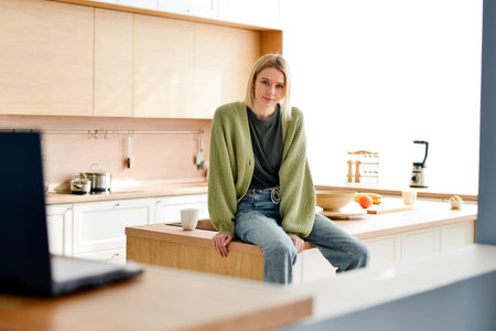 Portrait of young woman sitting on kitchen table