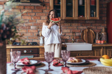 Woman at home eating watermelon in the kitchenの写真素材