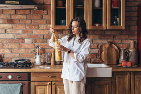Young woman in the kitchen takes the pasta to cook it.の写真素材
