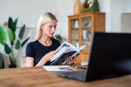 Female student studying, reading book at home