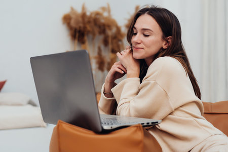 Woman looking smiling at laptop screen watching movie or TV seriesの写真素材