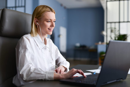 Woman sits in front of her laptop looking at screen and smilingの写真素材