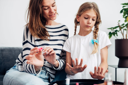 Mother and daughter doing manicure at home, painting nails with nail polishの写真素材