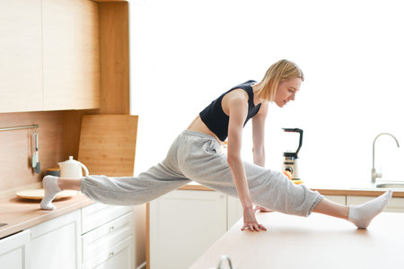 Woman doing the splits in kitchen between tables