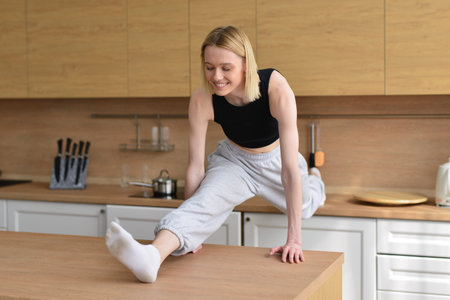 Woman doing the splits in kitchen between tables