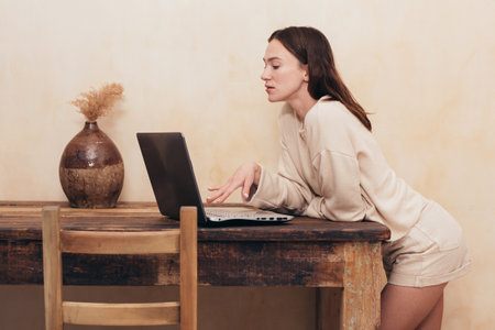 Young woman standing at desk with laptop computerの写真素材