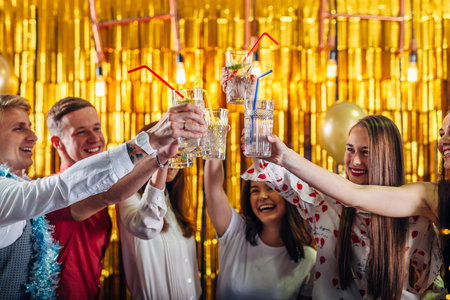 Group of friends toasting drinks at a party. People having wine indoors on a winter holidaysの写真素材
