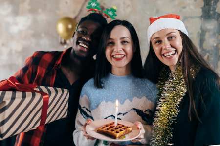 Woman holding birthday cake preparing to blow candle, friends around kissing cheeks.の写真素材