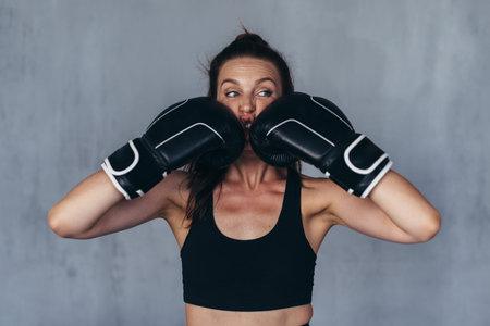 Young woman boxer jokingly beats herself.