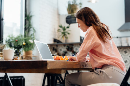 Girl works at home in the kitchen.の写真素材