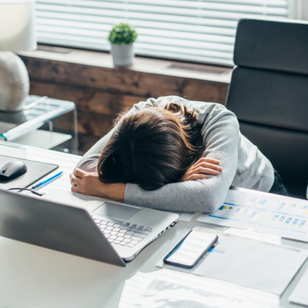 Woman at work in the office sleeping on the deskの写真素材