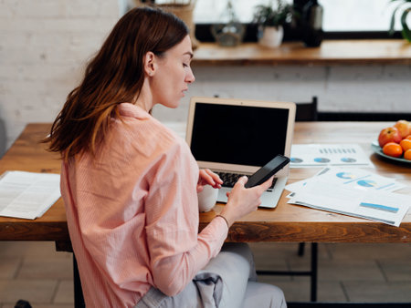 Young woman sitting at her desk with a smartphoneの写真素材