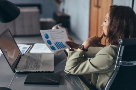 Woman sits at her desk reviewing documentsの写真素材