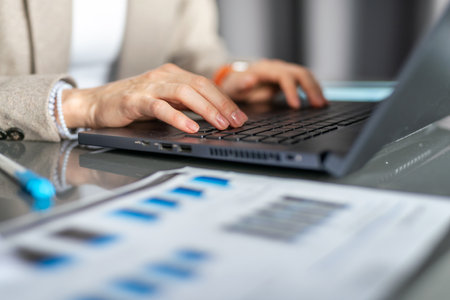 Female hands laptop keyboard documents desktop data analysis statistics report finance and investmentの写真素材