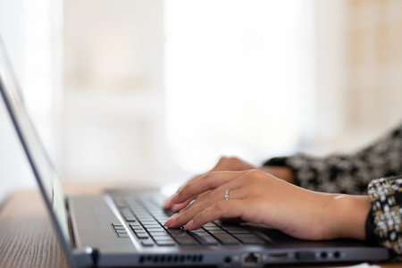 Female hands typing on laptop keyboard close-up