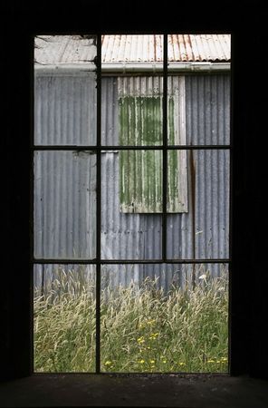 a corrugated iron shed framed by an old windowの写真素材