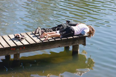 kids stare into the water at the end of a jetty on Lake Tutira, Hawke's Bay. New Zealand.の写真素材