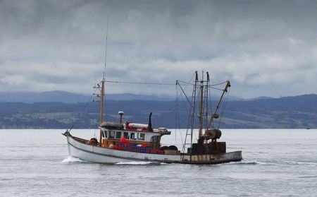 A rusty fishing boat chugs along the Hauraki Gulf in New Zealandの写真素材