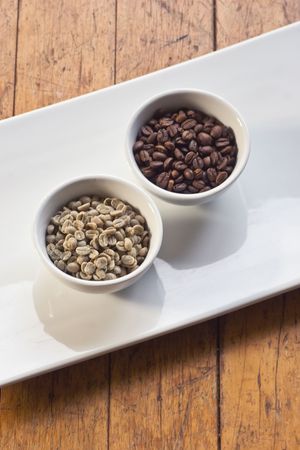Green beans and roasted coffee beans on white platterの写真素材