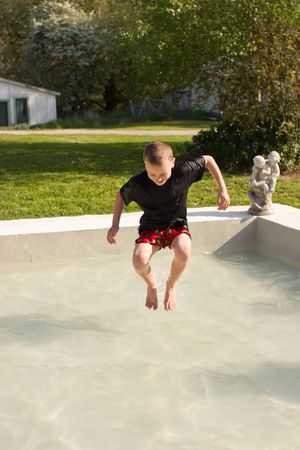 A young male boy splashes in a pool in his boxers and shirt on a warm spring dayの写真素材