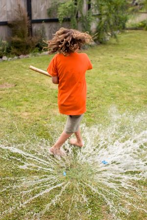 A young male playing with water balloons in the backyardの写真素材