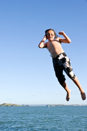 A caucasian male jumps off the wharf on Rangitoto Island, Hauraki Gulf, New Zealandの写真素材