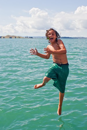 A teenage boy about to hit the water off the wharf at Rangitoto Island in the Hauraki Gulf of New Zealandの写真素材