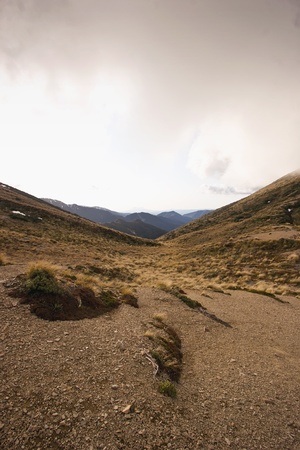The view down a valley from Armstrong Saddle in the Ruahine Ranges, North Island, New Zealand. Snow capped Mount Taranaki can be seen in the distance.の写真素材