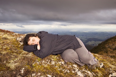 A woman has a little shuteye on a bed of moss on top of the Ruahine Ranges, North Island, New Zealandの写真素材