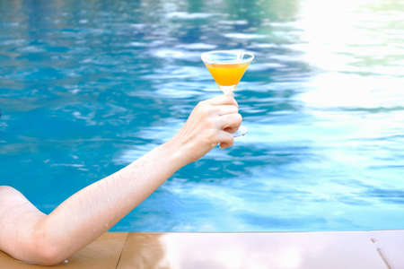 closeup arm of woman drinking beverage in poolside, happy life on summer seasonの写真素材