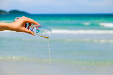 hands of female holding glasses of champagne on tropical sea beachの写真素材