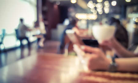 Blur cafe coffee shop with hand holding a cup and mobile phone , Retro styleの写真素材