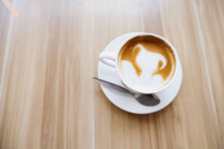 blurred a white cup of hot coffee latte art on the tableの写真素材