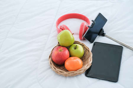 many fruit and electronic equipment on the bedの写真素材