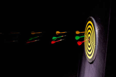 hurl darts on dartboard on black backgroundの写真素材