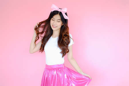 Portrait beautiful asian woman wearing white T-shirt and pink skirt on pink background, happy valentine day in love concept, emotions action, happy summer life with pink bow headbandの写真素材